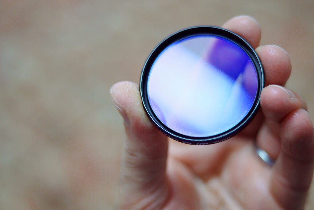 A hand holding a camera lens filter